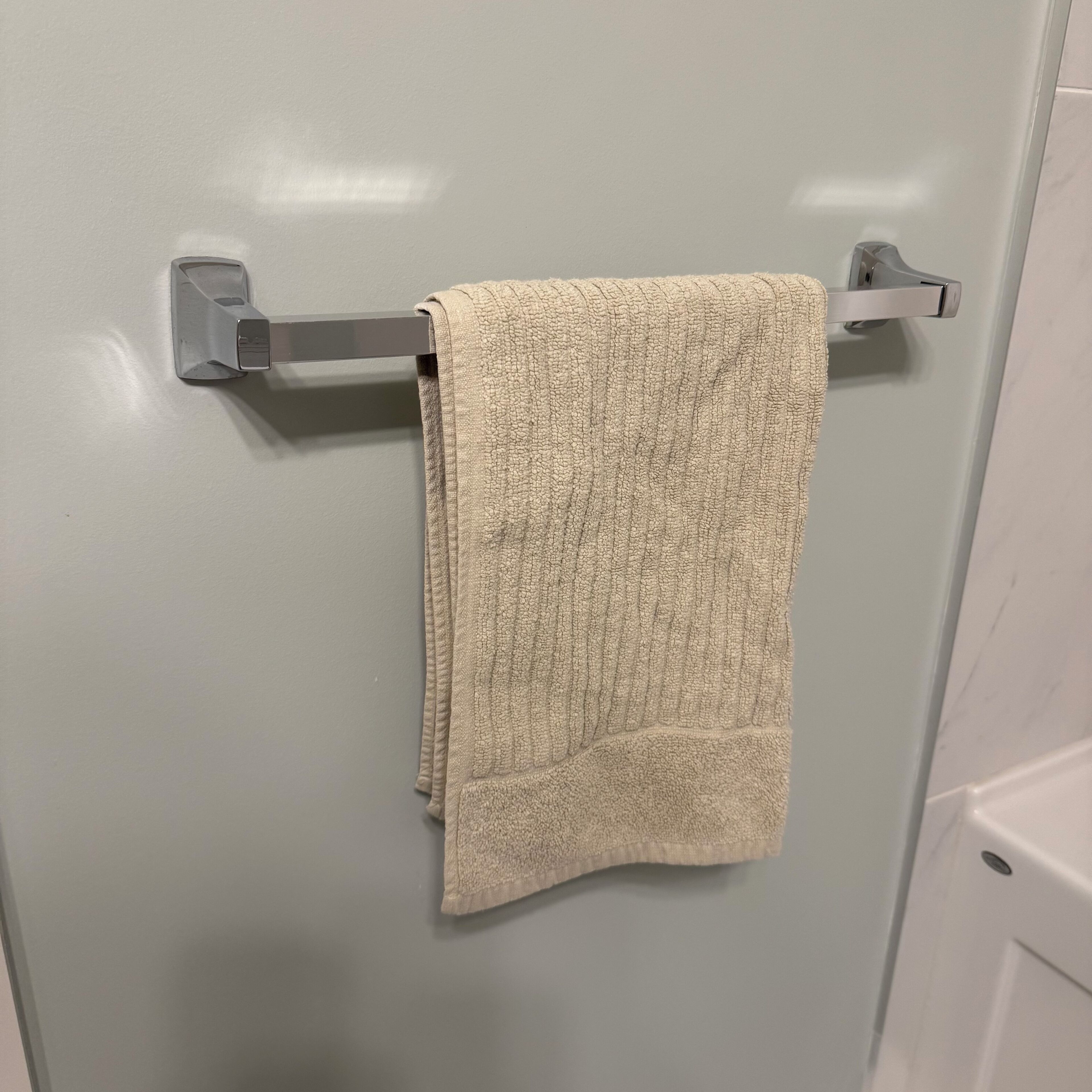 A towel hanging on a metallic towel rack attached to a bathroom wall.