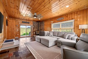 A cozy living room with a sectional sofa, a fireplace, and a view of the outdoors.