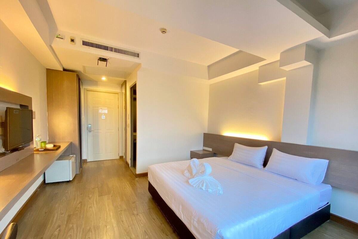 Quarto de hotel moderno com uma cama grande, mesas de cabeceira, uma TV e um closet espaçoso.