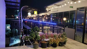 Eine Dachterrasse mit Topfpflanzen und Lichterketten.