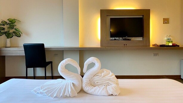Ein Hotelzimmer mit Bett, Schreibtisch, Stuhl, Fernseher und Pflanze.