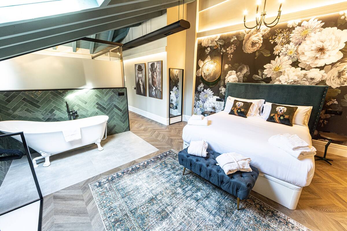 Un dormitorio moderno con una cama grande, una bañera y un papel tapiz con motivos florales.