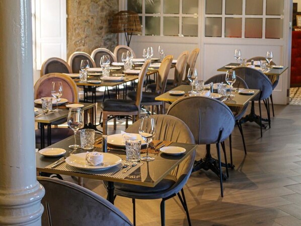 Un restaurante con mesas dispuestas para comer, sillas y una pared de piedra al fondo.