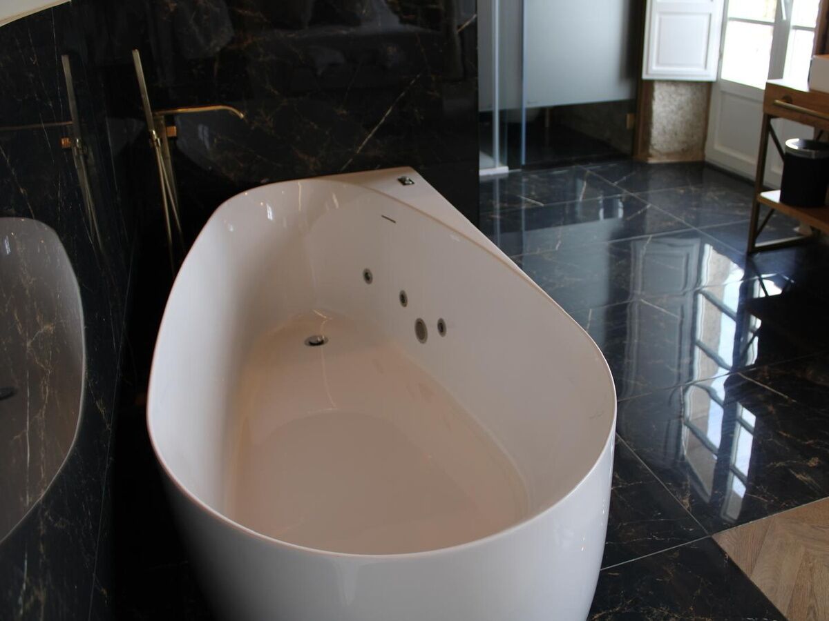 Een moderne badkamer met een vrijstaand bad, een glazen douchecabine en een marmeren vloer.