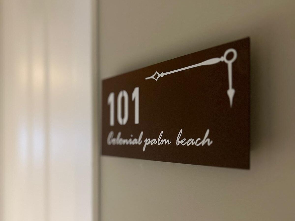 Un cartello con il numero 101 e la scritta 'Colonial Palm Beach' su un muro.