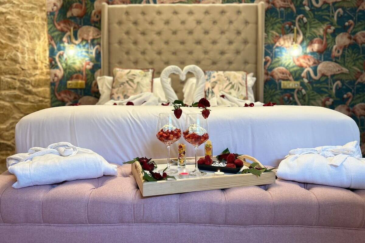 Un dormitorio con cama, almohadas, una bandeja con comida y bebidas, y un papel tapiz floral.