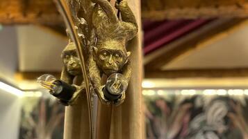 Een decoratieve messing lampfitting met een aapfiguur die een gloeilamp vasthoudt.