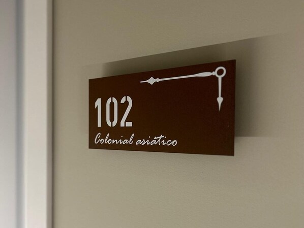 A wall-mounted sign with the number '102' and the text 'Colonial asiático' indicating a room or location.