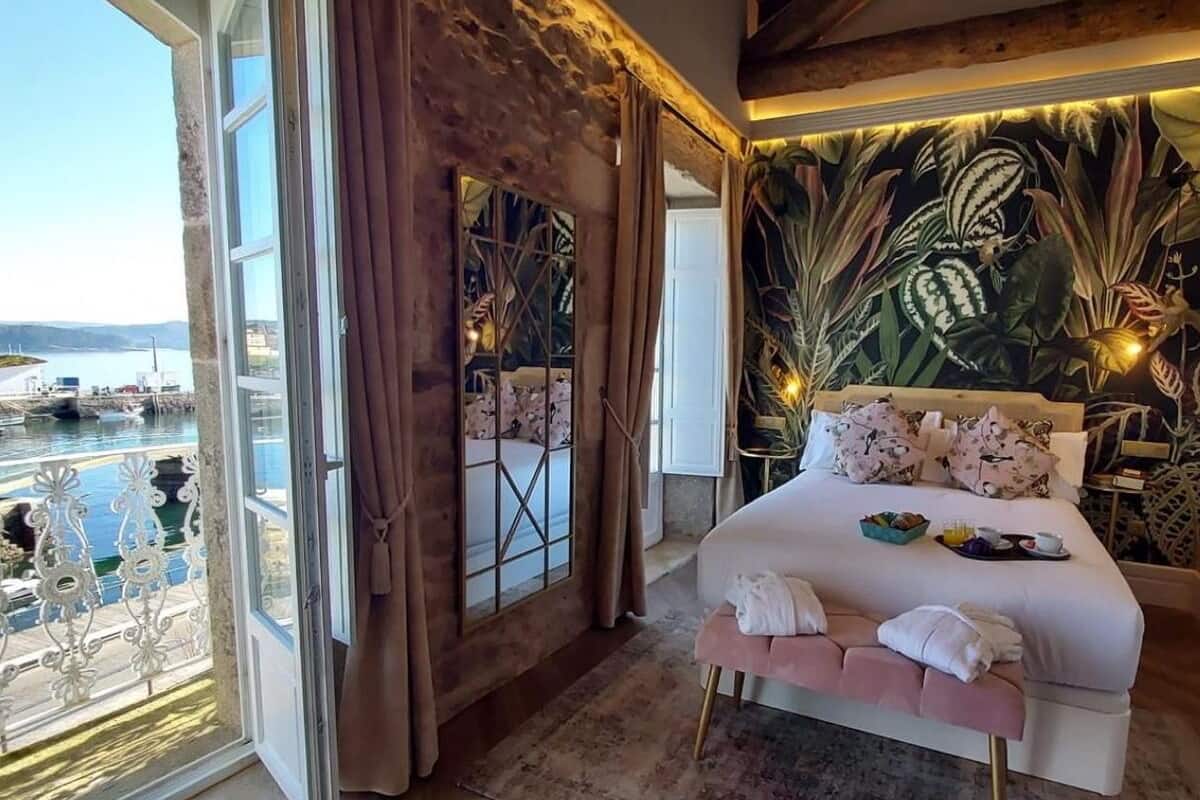Un dormitorio con una cama grande, vista al mar y un mural tropical en la pared.