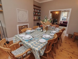 A dining area with a round table set for six, surrounded by wooden chairs.