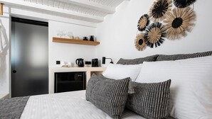 A modern bedroom with a bed, pillows, a coffee table, and wall decor. - K Town Suites Naxos Penthouse Apartment (Naxos)