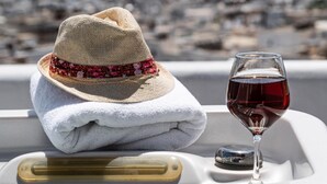 A boat with a straw hat and a glass of red wine on the deck. - K Town Suites Naxos Penthouse Apartment (Naxos)