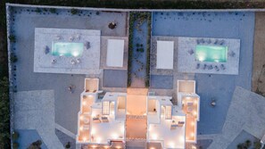 Luchtbeeld van een resort met twee zwembaden, een centraal ontspanningsgedeelte en een gastenverblijf.