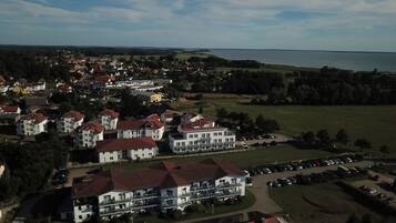 An aerial view of a residential area with multiple buildings, a parking lot, and a body of water in the background.