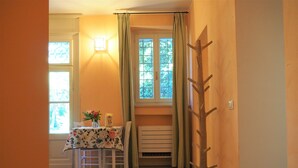 A dining area with a table set for two, a window with curtains, and a wooden tree sculpture on the wall. - Magnolia Apartment (Colombare)