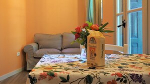 A room with a floral tablecloth, a vase with flowers, and a bag of Vialone Nano on the table. - Magnolia Apartment (Colombare)