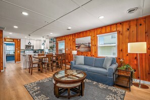 A living room with a sofa, coffee table, and dining area with chairs.