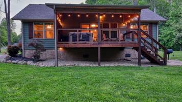 A two-story house with a covered deck and a staircase leading to the upper level.