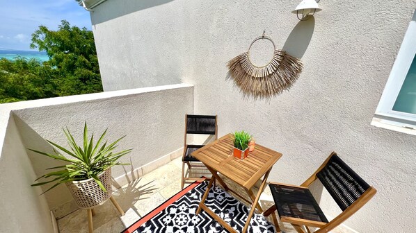Une table en bois avec des chaises, une plante en pot et une décoration murale sur un balcon.