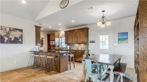A spacious kitchen with a central island, bar stools, and a dining table with chairs.
