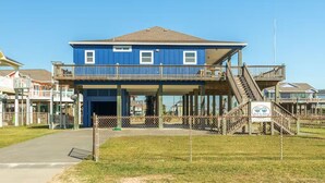 A two-story building with a blue exterior, a covered outdoor area, and a staircase leading to the upper floor.