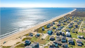 An aerial view of a coastal residential area with houses and a beach.