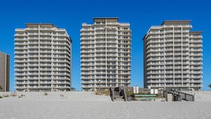 Three high-rise buildings with multiple balconies, a sandy beach in the foreground, and a clear blue sky. - 🌞🌞Gulf Views | Pool | Walk to Pier | 3BR Summerwind Center 704🌞🌞 (Navarre)