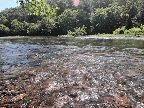Ein Fluss mit klarem Wasser und sichtbaren Felsen.