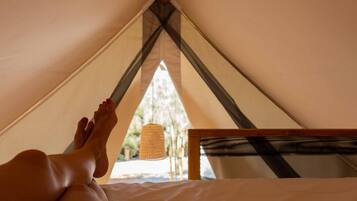 Ein Zelt mit Bett, einer Hängelampe und Blick ins Freie.