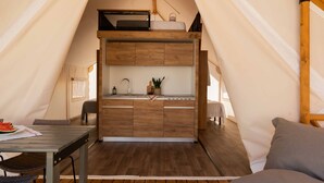 A tent with a kitchenette, a dining table, and a sleeping area.