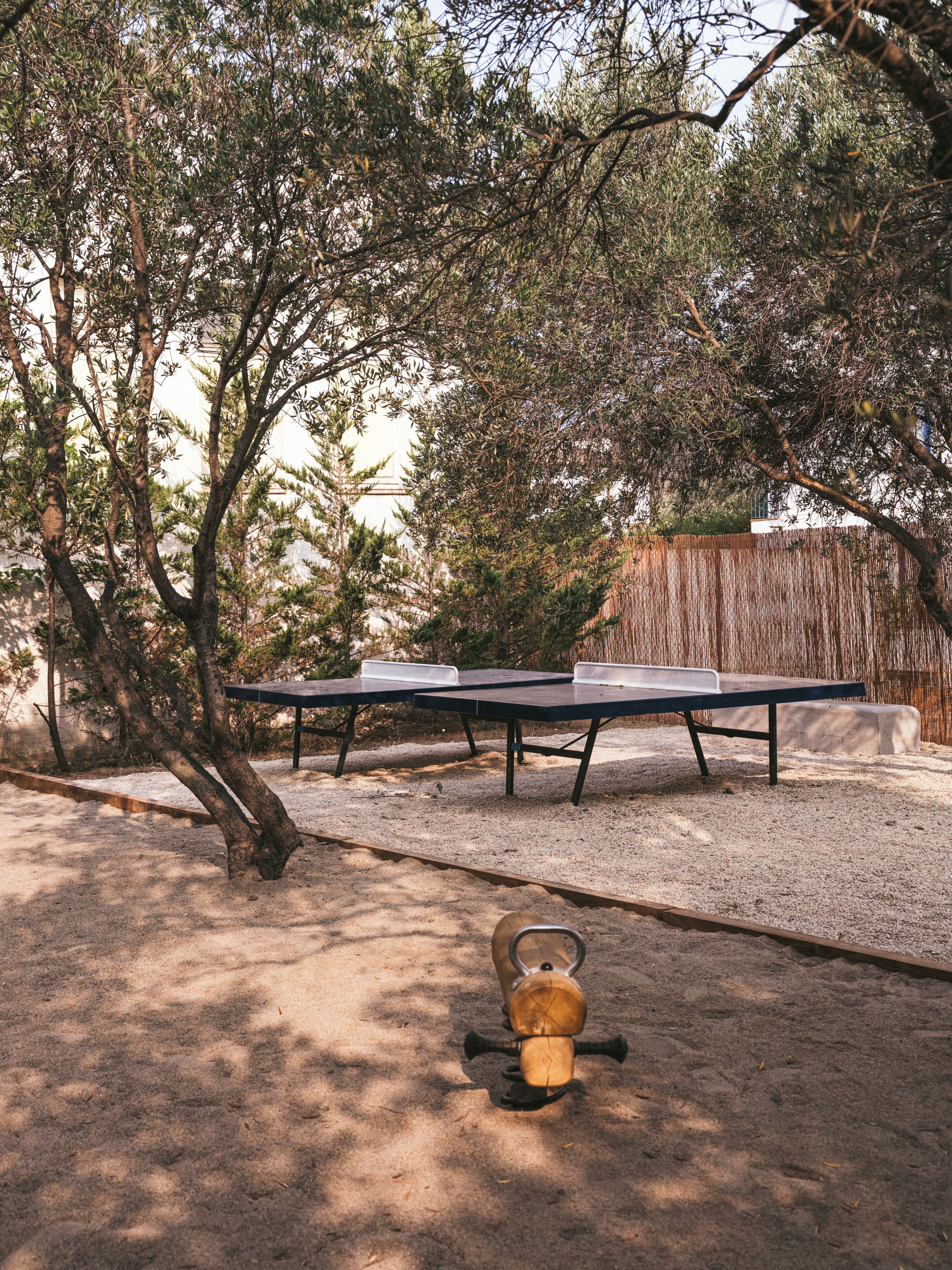 Une table et des chaises sont disposées à l’extérieur, avec des arbres en arrière-plan.