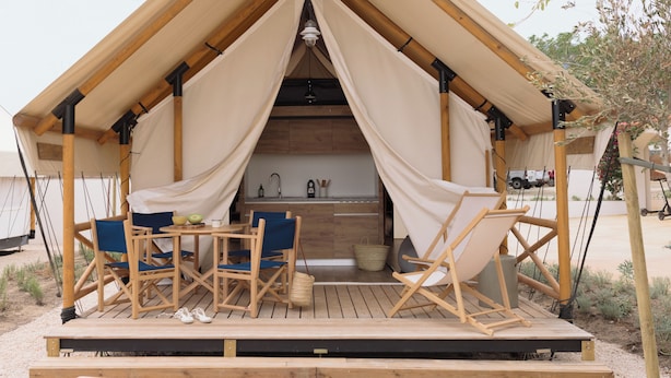 A wooden deck with a kitchen area, including a sink and cabinets, and a dining setup with chairs and a table.