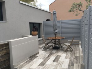 A patio area with a round wooden table, two chairs, a potted plant, and a grey fence. - 3-bedroom maisonette with a terrace, 5 minutes from the harbor and Super U, 10-minute walk to the beach (Cassis)