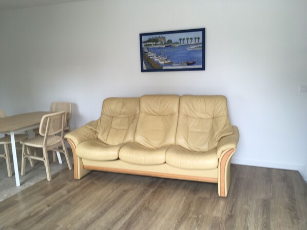 A beige leather sofa, a dining table with chairs, and a framed painting of a coastal scene on the wall. - 3-bedroom maisonette with a terrace, 5 minutes from the harbor and Super U, 10-minute walk to the beach (Cassis)