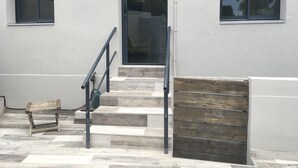 A building exterior with a staircase, a bench, and a wooden gate.
