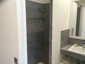 A bathroom with dark tiled walls, a white sink, and a mirror. - 3-bedroom maisonette with a terrace, 5 minutes from the harbor and Super U, 10-minute walk to the beach (Cassis)