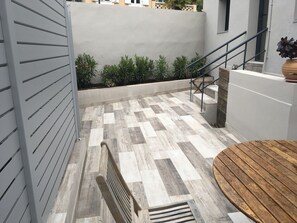 A modern outdoor area with a checkered floor, a wooden bench, a metal staircase, and a potted plant.