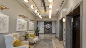 Een moderne hotellobby met een receptiebalie, een zithoek en een lift.