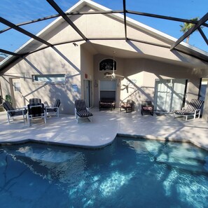 Un área de piscina con sillones reclinables y un ventilador de techo.