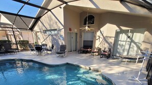A swimming pool with a curved edge, surrounded by lounge chairs and a covered patio area. - 4BR Disney Villa w/ Private Pool - Lake Berkley Resort (Kissimmee)