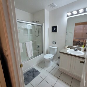 A bathroom with a glass-enclosed shower, a toilet, a sink, and a mirror.