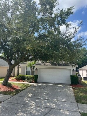 A residential driveway leading to a garage with a tree in the foreground. - 4BR Disney Villa w/ Private Pool - Lake Berkley Resort (Kissimmee)