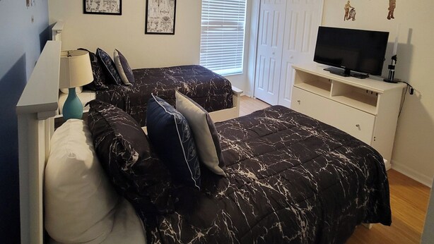 A bedroom with a bed, a TV, a ceiling fan, and artwork on the walls. - 4BR Disney Villa w/ Private Pool - Lake Berkley Resort (Kissimmee)
