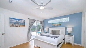 Un dormitorio con cama, mesitas de noche, ventilador de techo y vistas al exterior.