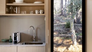 Una cocina moderna con armarios de madera, un lavamanos y vistas a un bosque a través de una puerta de cristal.