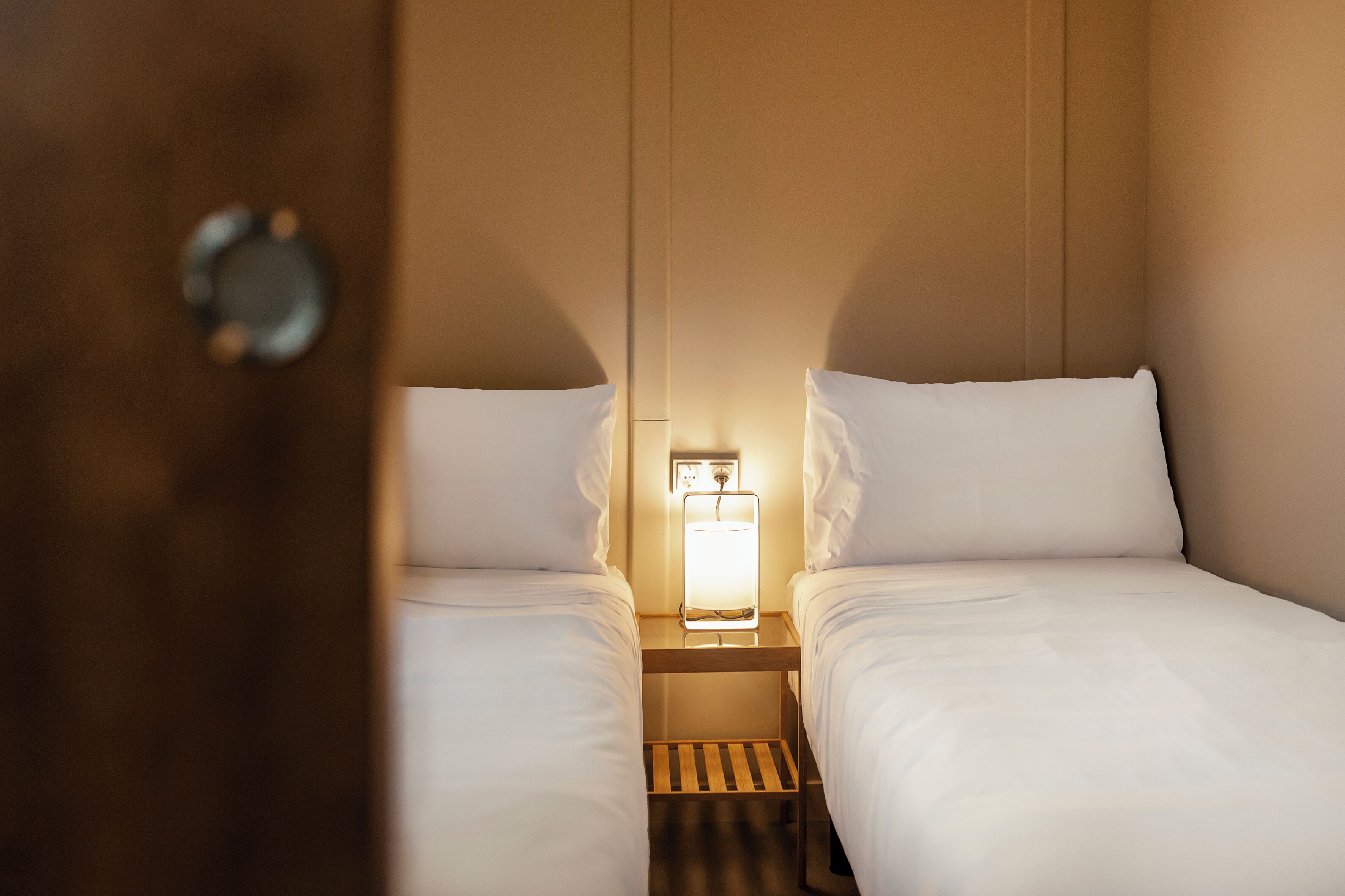 Une chambre d’hôtel avec deux lits, une table de chevet avec une lampe et un plancher en bois.