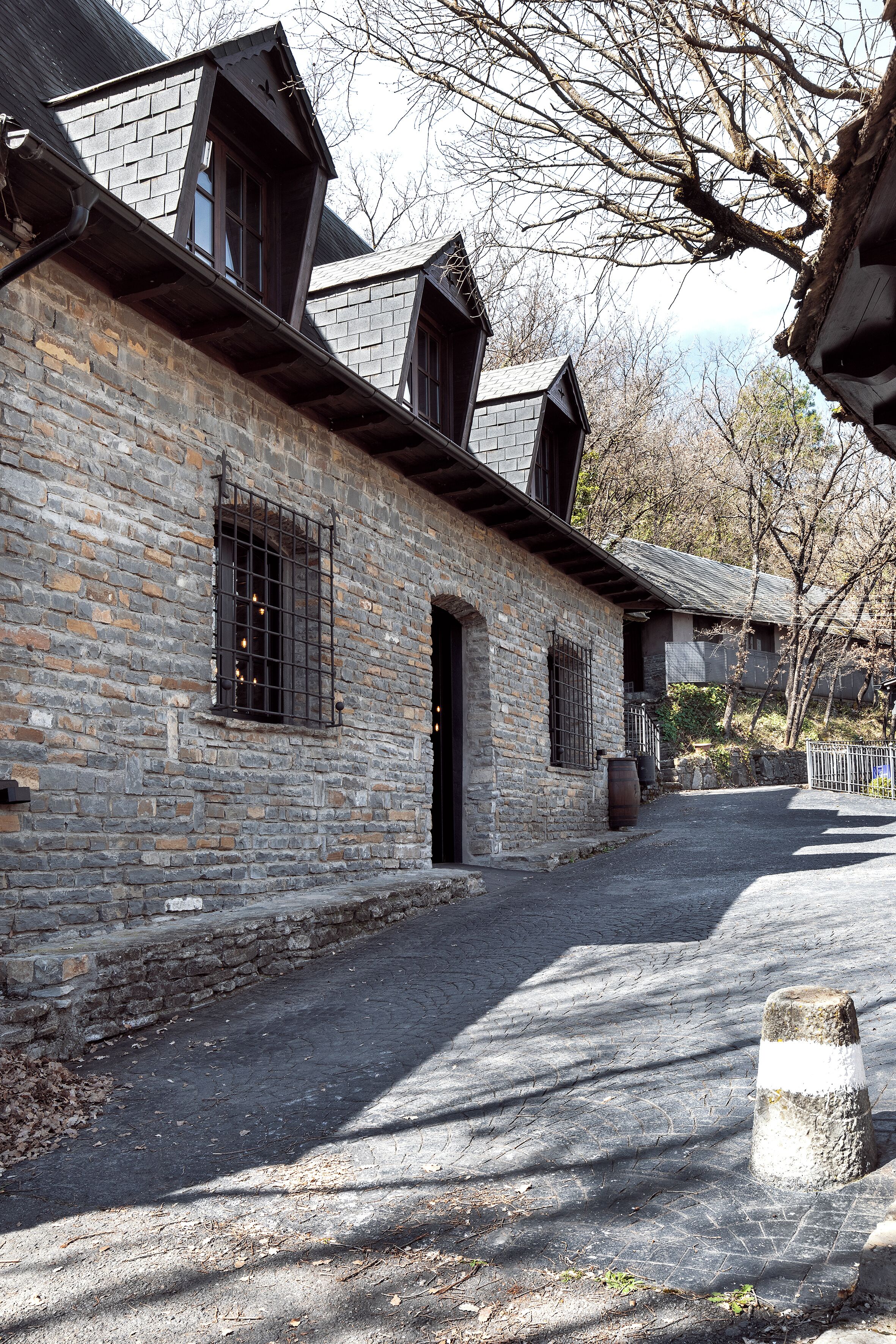 A stone building with a sloped roof, a wooden door, and a window with metal bars.