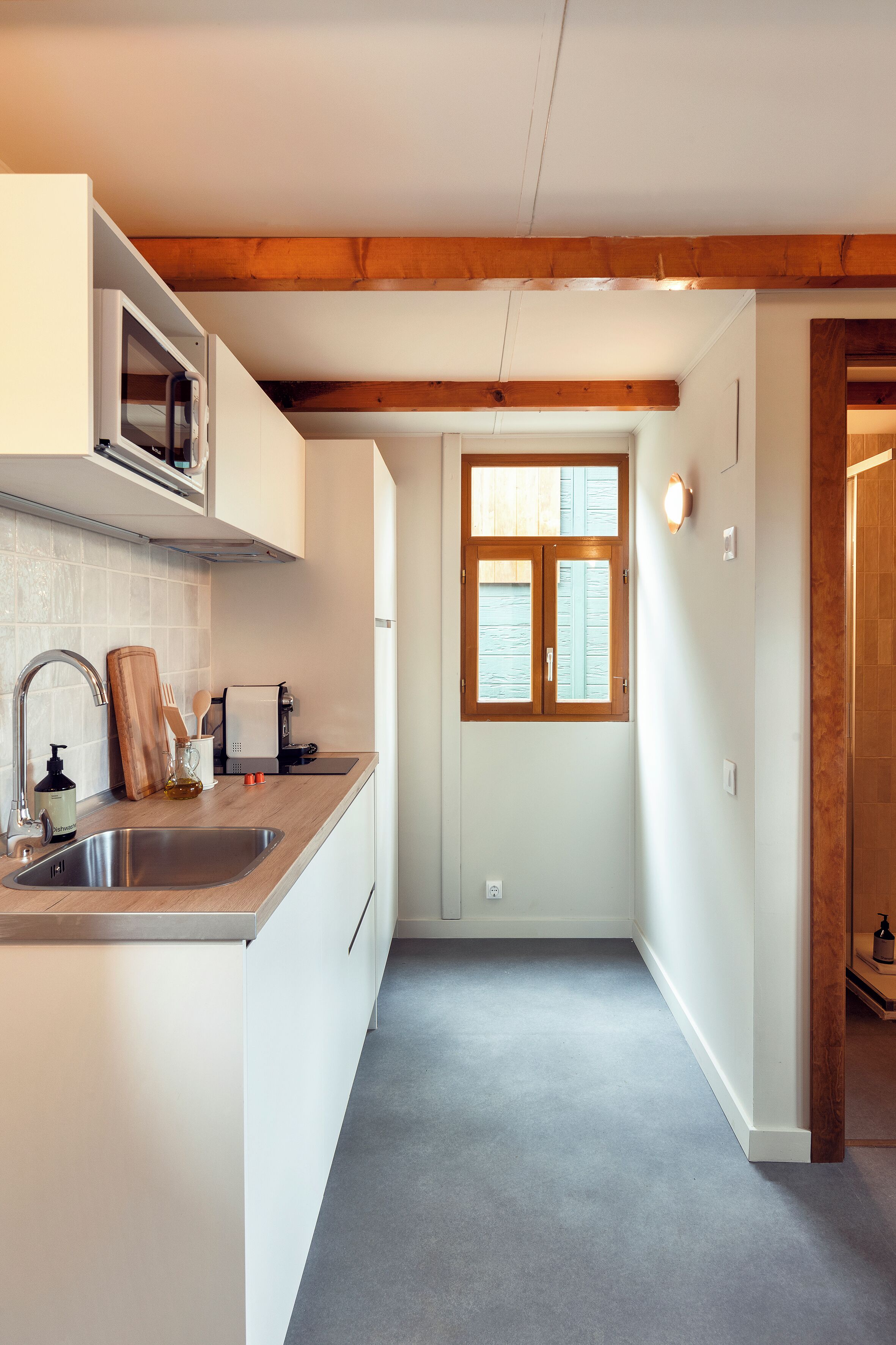 A kitchen with a wooden ceiling, a window, and a sink.