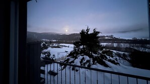 Un balcón con un paisaje nevado y la luna en el cielo.