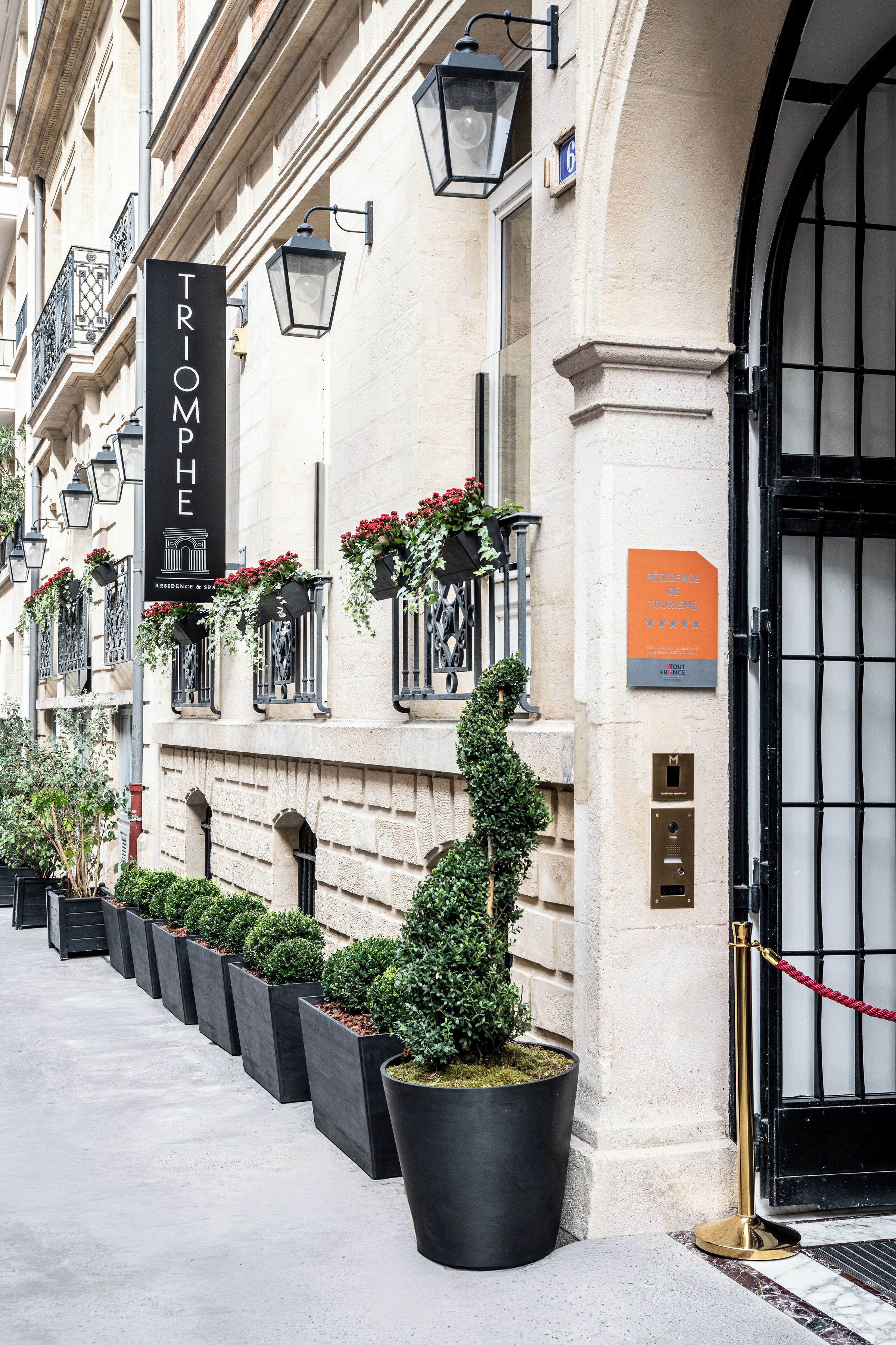 Une façade d’immeuble avec une enseigne noire sur laquelle on peut lire : « TRIMPH, résidence et spa ».
